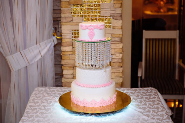istock White multilevel wedding cake decorated with pink cream flowers on table. Candy bar concept 927455424