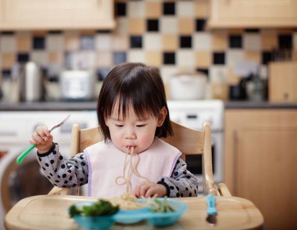istock Baby girl eating messy at home kitchen 927460360