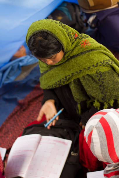 istock Girl student in Indian village school looks down on her work 927468112