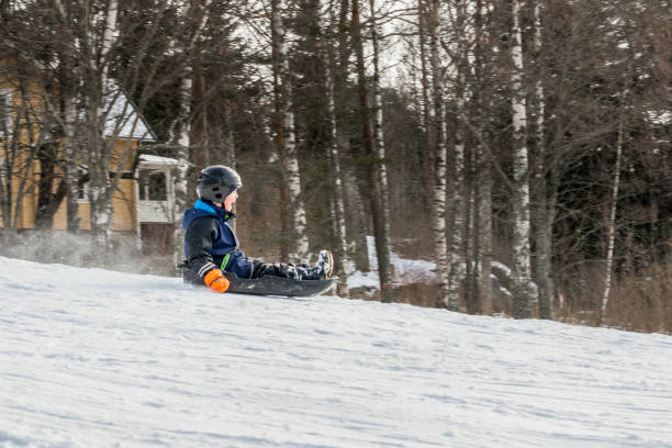 istock A child riding at high speed a sledge downhill, profile view. 927468158