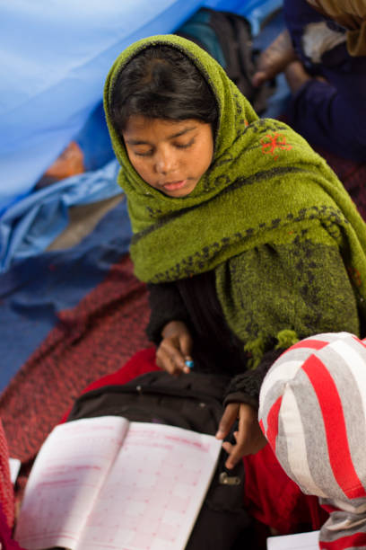 istock Girl student in Indian village school concentrates on her work 927468170