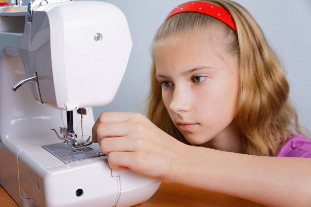 istock A teenager girl learns to thread a needle into a modern sewing machine 927468854