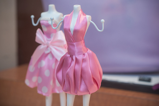 closeup of mini mannequin with pink dress in fashion store for women