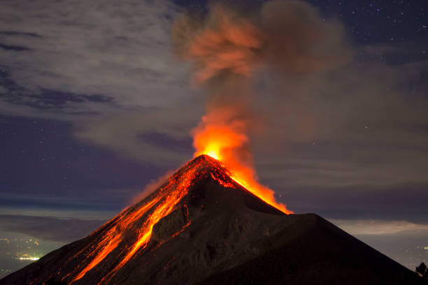Volcano eruption captured at night, from the Volcano Fuego near Antigua, Guatemala Picture allows to see a lot of clear lava, as well as a few stars and the city lights in the distance. Picture shot around 10:00 PM, on the rim of the Acatenango Volcano which is right next to the volcano Fuego. active volcano photos stock pictures, royalty-free photos & images