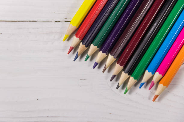 istock Colored pencils on white wooden desk. Top view, copy space 927496654