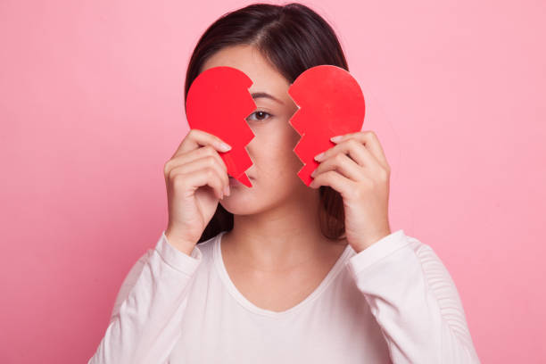 Broken love concept with torn paper heart on crashed glass smartphone touchscreen