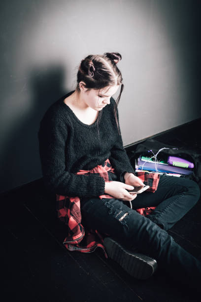 młoda alternatywna dziewczyna siedząca na czarnej podłodze z torbą szkolną - pierced punk goth teenager zdjęcia i obrazy z banku zdjęć