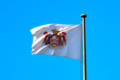 MONACO. flag with the coat of arms of Monaco over the prince's dwarf.