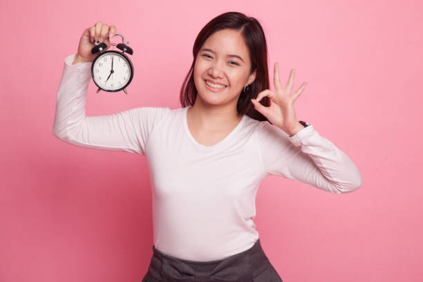 istock Young Asian woman show OK with a clock. 927504018