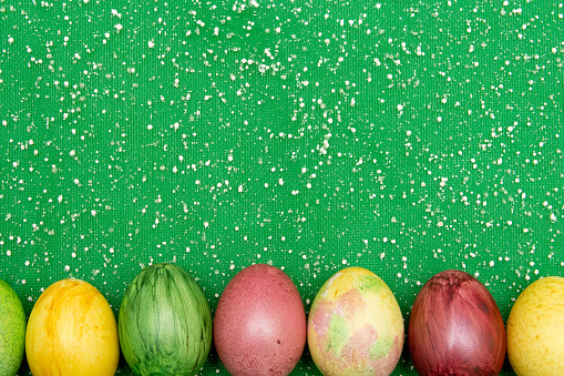 Colorful easter eggs on green organza fabric background. Eggs handmade new style of colouring . Pattern, easter concept.