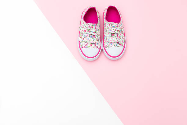 白とピンクの背景の上に赤ちゃんのためのスニーカー。フラットを置く - saddle shoes ストックフォトと画像