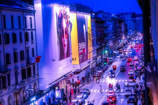 A busy night on Corso Buenos Aires, Milan Italy. View from above of lights on the street from billboards, neon signs and headlights illuminating the street in vivid color.