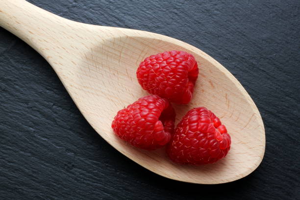 istock Raspberries on wooden spoon with slate background 927517300