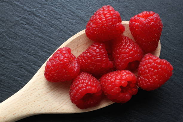 istock Raspberries on wooden spoon with slate background 927517366