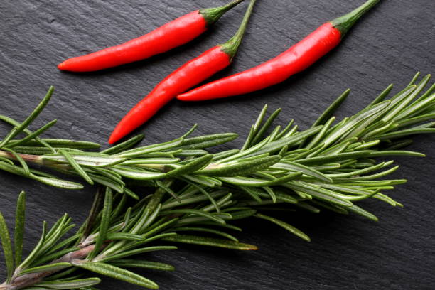 Red hot thai chili pepper with rosemary on slate board, top view, close-up