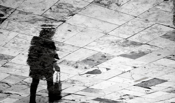istock Blurry woman silhouette reflection on rainy patterned sidewalk 927544306