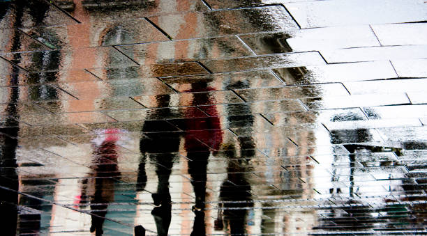 istock Blurry reflection silhouette of  people walking in the rain 927544472