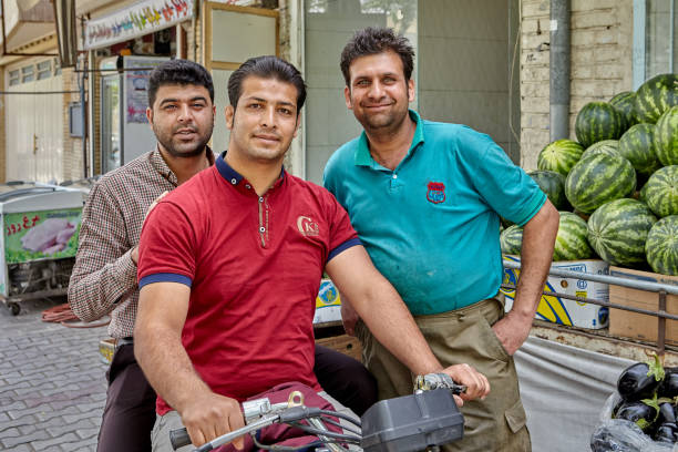Kashan, Iran - April 27, 2017: Three street vendors are posing for a photographer near a watermelon pile.