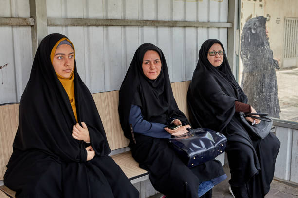 tre flickor i svart islamiska kläder väntar på bussen. - iranian girl bildbanksfoton och bilder