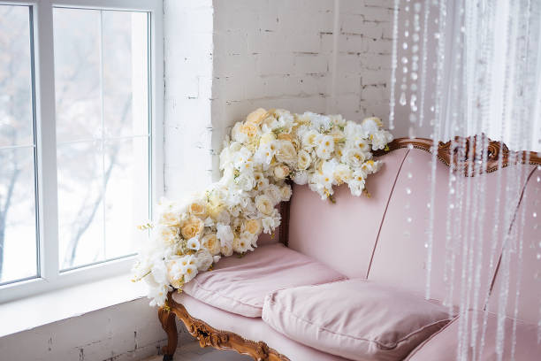 Vintage style sofa decorated with flowers in loft interior room with big window