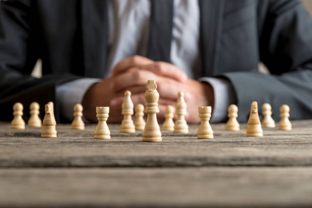 istock Man wearing suit sitting in front of white chess 927548578