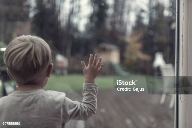 Toddler Boy Staring Out Of A Window In Evening Light Into The Garden Stock Photo - Download Image Now