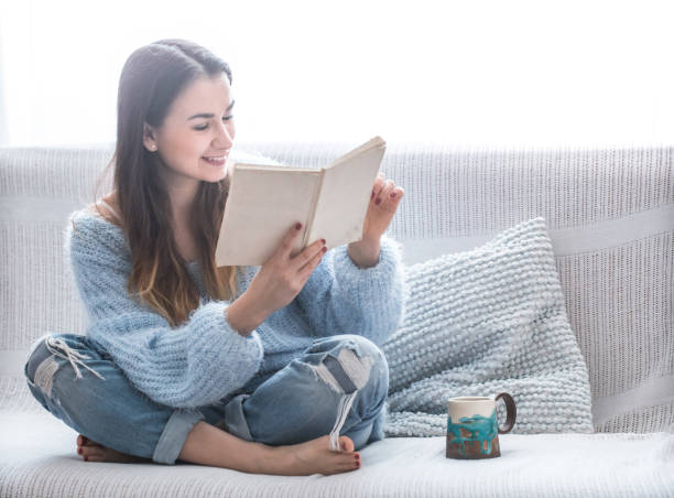 istock girl on the couch reading a book 927573368