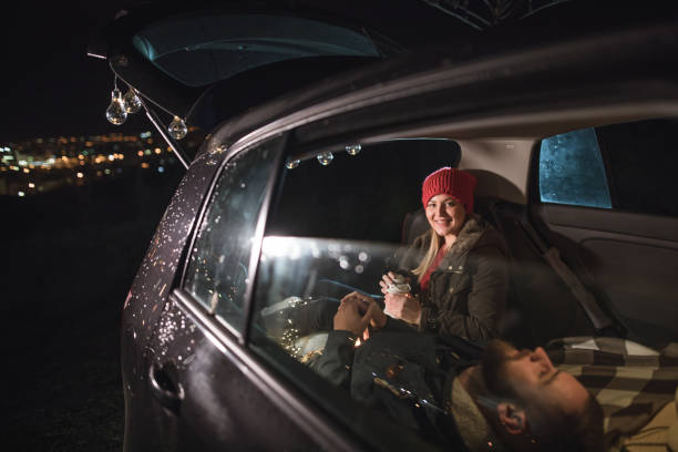 istock Young couple in love sitting in car open trunk 927573904