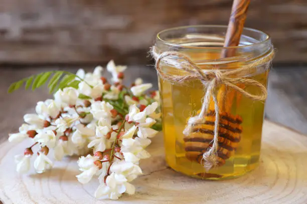 Acacia honey and flowering acacia on wooden table