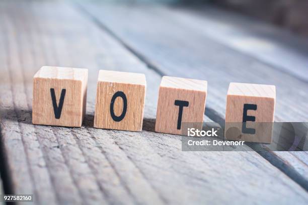 Macro De La Votación De La Palabra Formada Por Bloques De Madera Sobre Un Suelo De Madera Foto de stock y más banco de imágenes de Votar