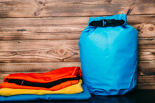 Swimming waterproof bag and clothes on wooden background