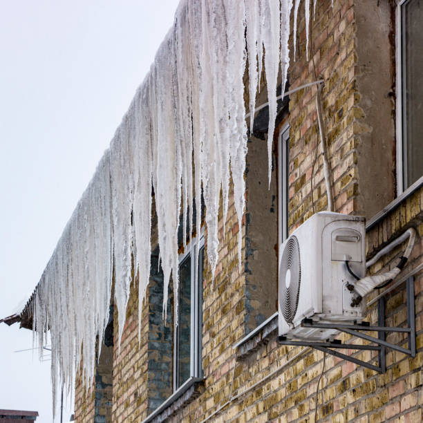 istock Melting icicles under the roof and clouds in blue sky 927599842