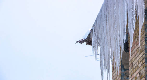 ghiaccioli che si sciolgono sotto il tetto e nuvole nel cielo blu - icicle hanging snow moving down foto e immagini stock