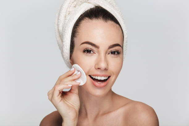 istock young woman cleaning face with cotton disk isolated on white 927603786