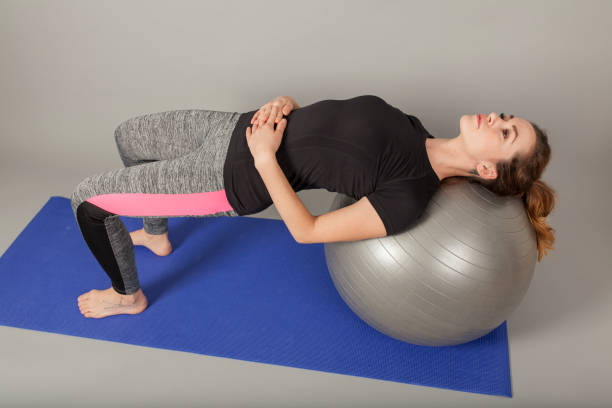 istock young women rolling backwards on gymnastic ball 927604108