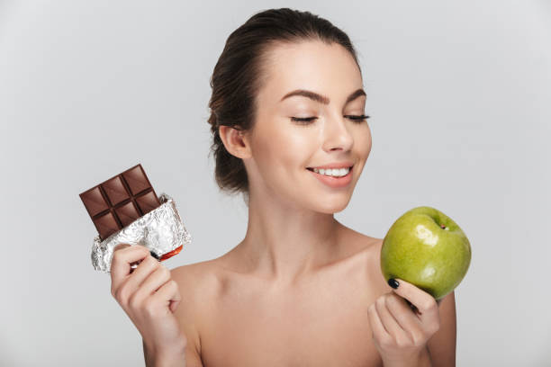 istock young woman making choice between apple and chocolate isolated on white 927604304
