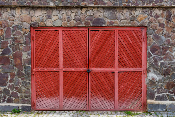 istock Old red wooden gate with lock in a stone fence 927607646