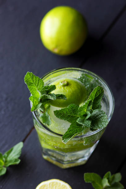 istock Minimalist cocktail, mojito on a dark background, summer cocktail with lime and mint, refreshing drink with lemon, fresh mint for cocktail, celebratory drink with ice, vegan, copy space, blank for designer, art 927611438
