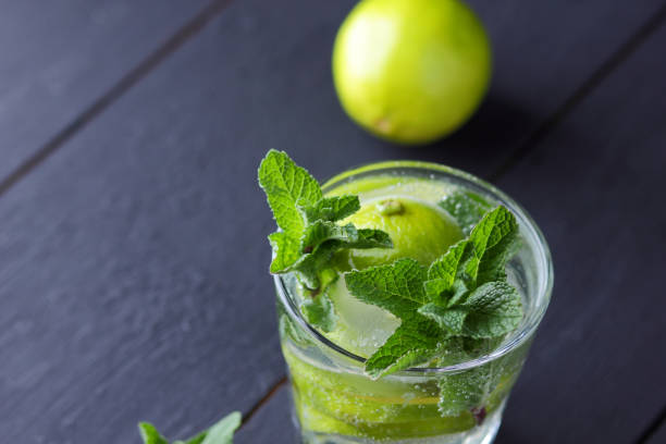 istock Minimalist cocktail, mojito on a dark background, summer cocktail with lime and mint, refreshing drink with lemon, fresh mint for cocktail, celebratory drink with ice, vegan, copy space, blank for designer, art 927611518