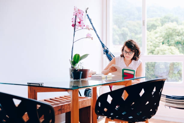 istock Young woman reading a book at home 927617222