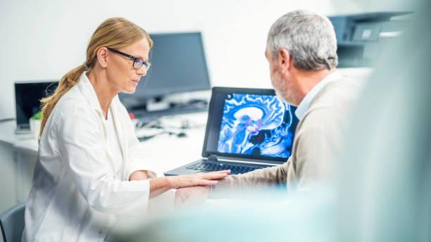 Brain tumour diagnosis Female doctor consoling her patient who has brain cancer which is visible from a picture on a laptop in the centre. brain tumour photos stock pictures, royalty-free photos & images