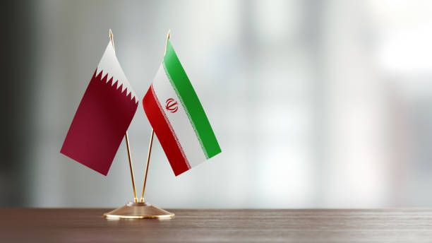 istock Qatari And Iranian Flag Pair On A Desk Over Defocused Background 927620810