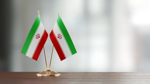 istock Iranian Flag Pair On A Desk Over Defocused Background 927623112