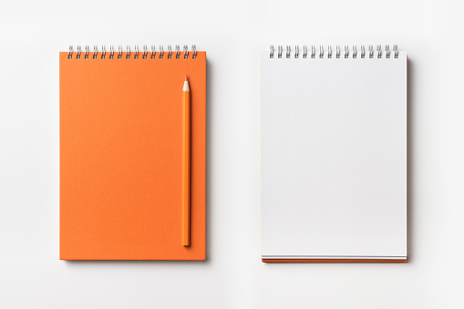 Top view of orange spiral notebook and color pencil collection