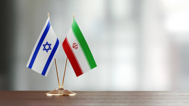 Israeli And Iranian Flag Pair On A Desk Over Defocused Background