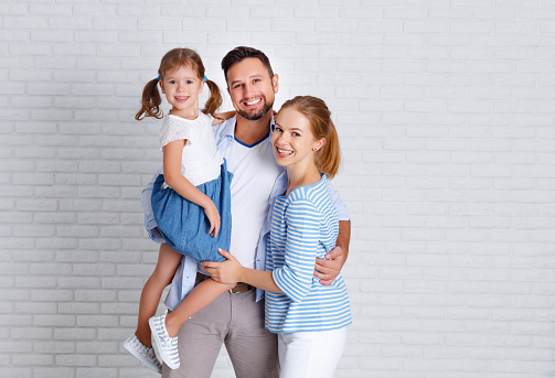 happy family mother father and child daughter near an empty brick wall