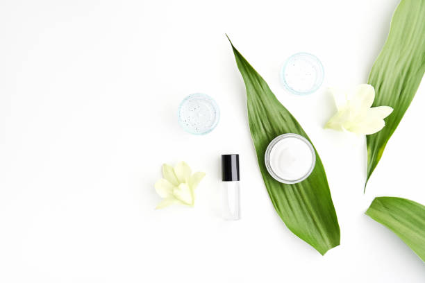 White cream bottle placed, Blank label package for mock up on a green foliage background and flowers. The concept of natural beauty products.