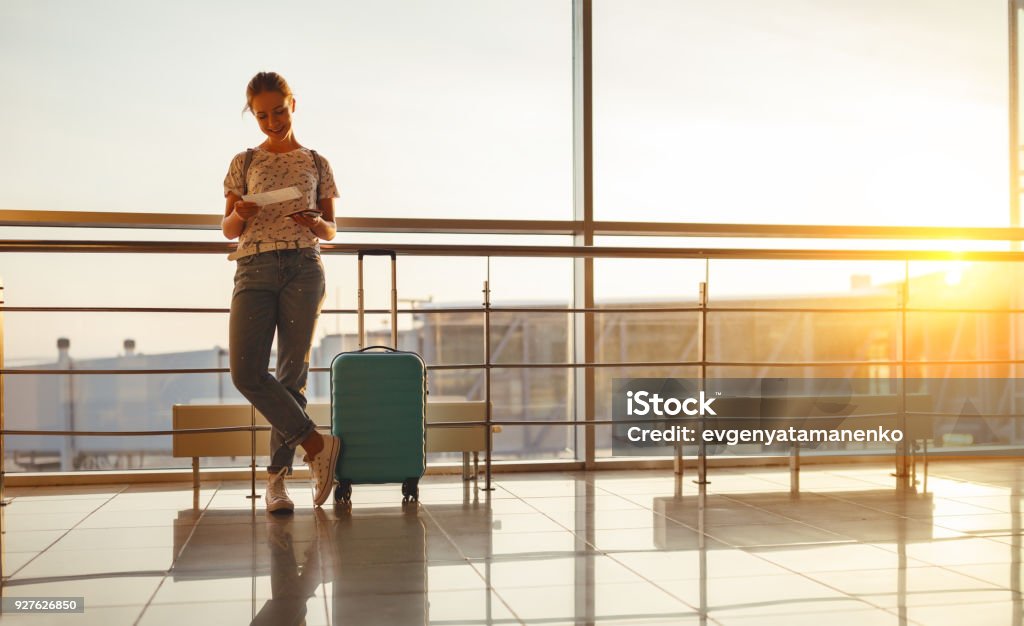 giovane donna in attesa di volare in aeroporto alla finestra con valigia - Foto stock royalty-free di Viaggio