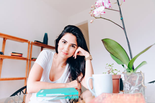istock Young woman reading a book at home 927632898