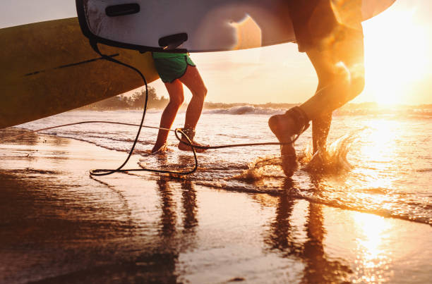 istock Son and father surfers run in ocean waves with long boards 927652854